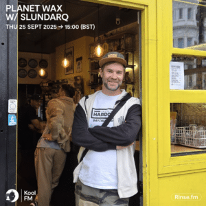 A man in casual clothing stands and smiles at the entrance of a yellow-fronted shop, ready to share his story. Event details for "Planet Wax w/ Slundarq" on 25 Sept 2025 are displayed in the top left corner.